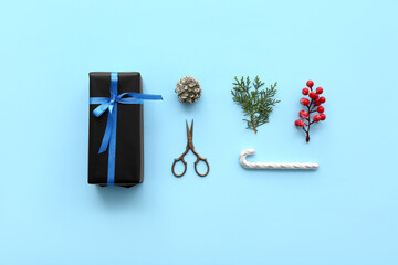 Christmas gift box with coniferous branch, rowan, cone and candy cane on blue background