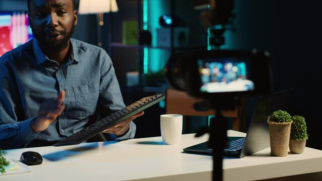 Content creator in living room studio films mechanical keyboard review for online streaming platforms. Trending media star hosts technology focused internet show, unboxing computer peripherals