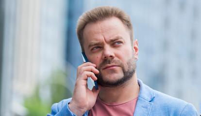 portrait of a confident focused businessman with a smartphone on the street