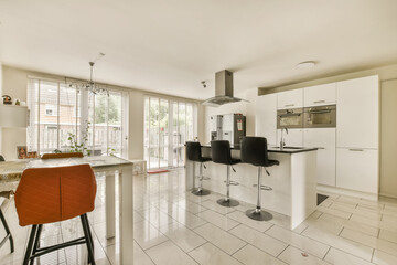a kitchen and dining area in a house with white tiles on the floor, red bar stools and an orange...