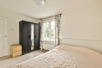 a bedroom with a bed, dresser and wardrobe in the corner to the left is an open door that leads to a window
