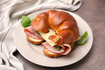 Tasty crescent roll with ham, cheese and basil on grey table, closeup