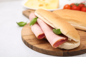 Delicious sandwich with ham and basil on white table, closeup