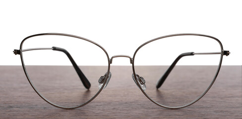 Stylish glasses with metal frame on wooden table against white background