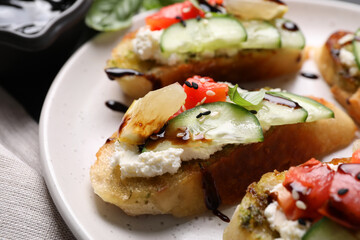 Delicious bruschettas with balsamic vinegar and toppings on plate, closeup