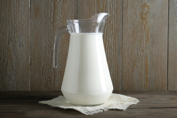 Jug of fresh milk on wooden table