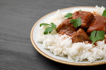Delicious goulash with rice on grey wooden table, closeup