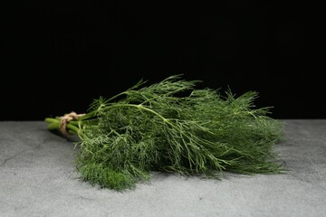 Bunch of fresh dill on light grey table against black background