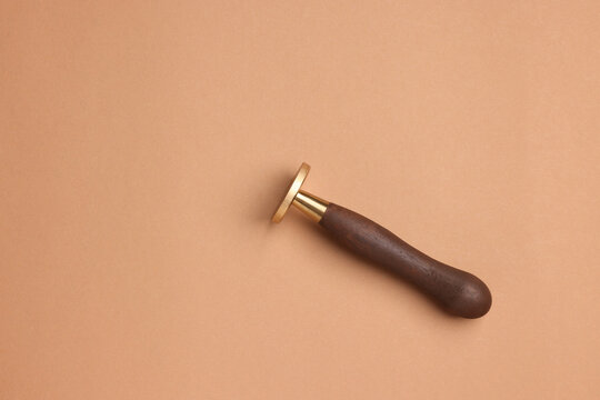 One stamp tool with wooden handle on light brown background, top view. Space for text
