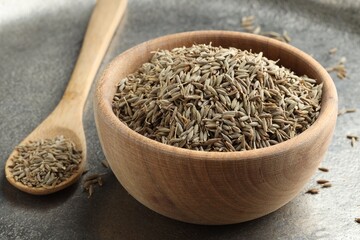 Bowl of caraway seeds and spoon on grey table, closeup - obrazy, fototapety, plakaty