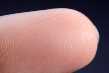 Finger with friction ridges on dark background, macro view