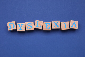 Wooden cubes with word Dyslexia on blue background, flat lay