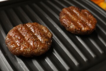 Delicious hamburger patties on electric grill, closeup
