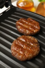 Delicious hamburger patties on electric grill, closeup