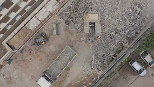 Aerial drone view of a demolition site. Excavator loading concrete and steel rubble onto the truck.