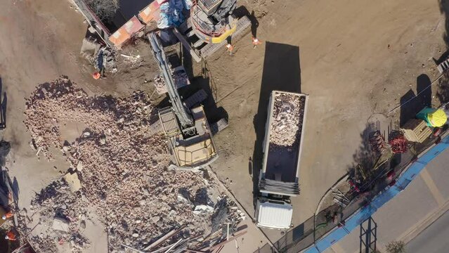 Aerial drone view of a demolition site. Excavator loading concrete and steel rubble onto the truck.