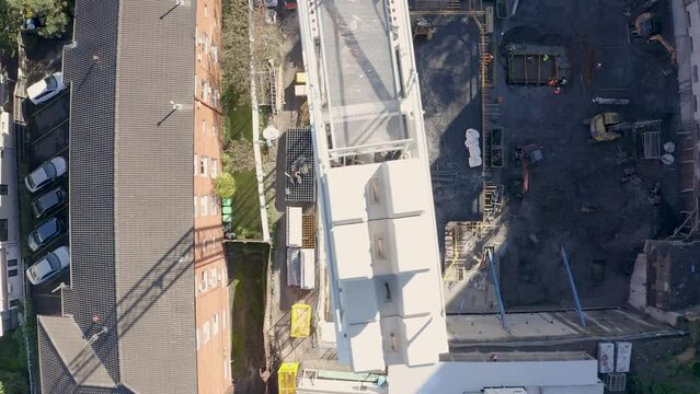 Aerial flight over a demolition site with high tower cranes. Heavy machinery and construction workers in safety gear..