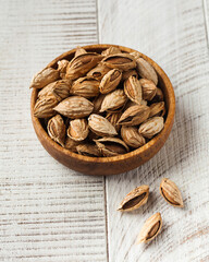 Almond nuts in a shell in a wooden plate on a white wooden background. Nuts. 