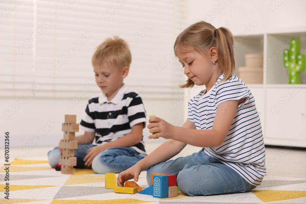 Poster Little children playing with building blocks indoors. Wooden toys