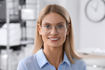 Portrait of beautiful businesswoman in glasses indoors. Confident lady with blonde hair looking into camera