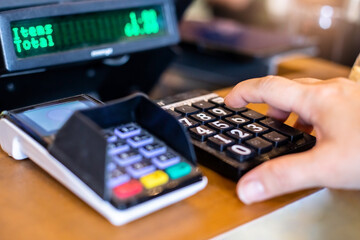 Selective focus to finger of women inserting password or pin code login on machine keypad of payment terminal.