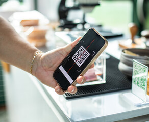 Selective focus to hand holding smartphone to scanning QR code on tag. Customer hand making payment to accepted generate digital pay without money.