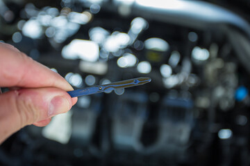 Car engine with oil funnel and person checking the oil dipstick for oil level