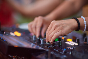 DJ is mixing music with deejay controller at outdoor summer pool or beach party - nightlife people...