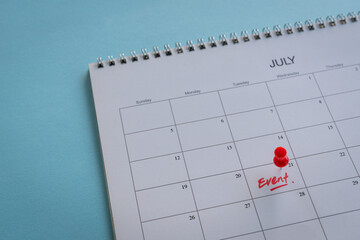 Calendar with word event and red pushpin. On blue desk background, copy space.