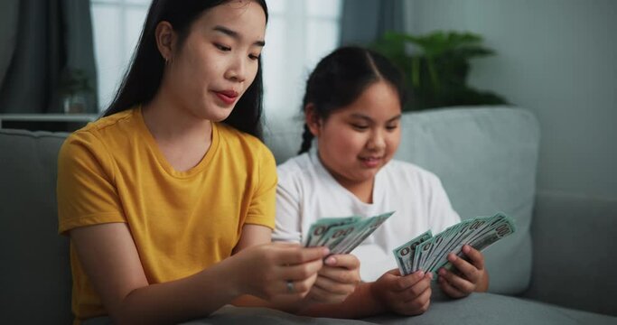 Footage of young women and teen girl counting cash money on sofa in the living room at home,Happy counting dollars banknote.