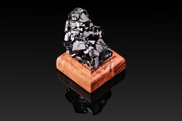 mountain crystal mineral of black color on a stand made of wood