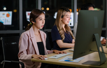 Fototapeta na wymiar Asian professional successful female businesswomen assistant night shift call center helpline in formal business outfit and microphone headphones sitting smiling talking helping customers online