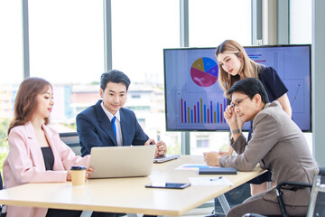 Fototapeta premium Asian professional successful male and female businessman businesswoman partnership colleagues in formal business suit sitting standing listening to presenter in meeting room in company office