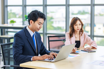 Closeup Asian professional successful male female businessman businesswoman partnership colleagues in formal business suit sitting  in meeting room in company office