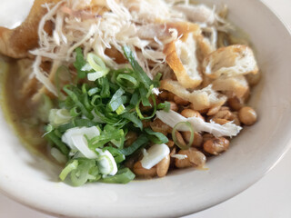 Chicken Porridge, traditional food from Indonesia called bubur ayam consist of white rice porridge, shredded chicken, cakwe, fried soybean, crackers, leek. Selective focus