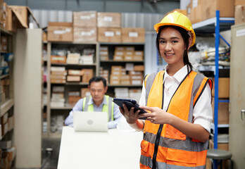 portrait worker working on tablet beside cardboard box on shelf in warehouse storage
