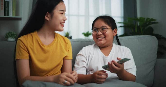 Footage of young woman giving dollars money with teen girl for doing great work at home.