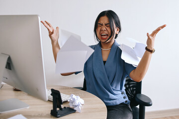 Asian businesswoman or female office worker screaming, shouting and throwing up papers at her...