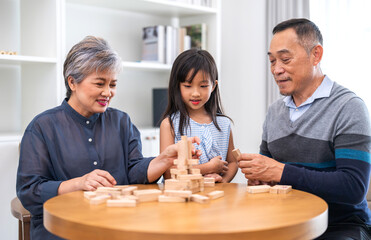 Portrait of happy love asian grandfather with grandmother and asian little cute girl enjoy relax at home.Young girl with their laughing grandparents smiling together.Family and togetherness