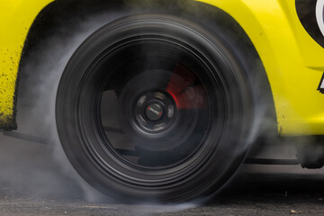 Drag car burning tire, Warm up tire before competition, Drag car wheel, Spinning wheel and smoke, Drag racing car burns rubber tires preparation for race.