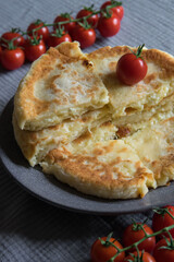 Homemade cheese filled savoury pies khachapury on grey plate served with tomatoes. Selective focus