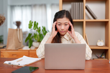 office worker asian woman uses both hands to gently massage his forehead. After intending to work on a notebook computer With boredom with routine work Have a headache because of stress