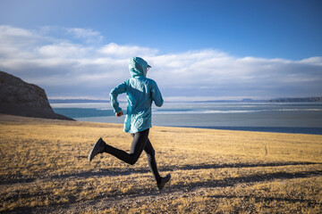 Woman trail runner cross country running in lakeside mountains