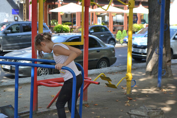 The girl goes in for sports on the Playground on the street.