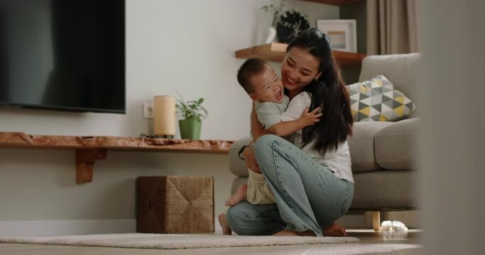 Asian mom and baby boy together. Little baby kid running into mom arms, laughing smiling enjoying life cuddling. Happy precious cheerful moments spent together, warm relationship between mother and