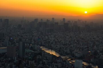 夕日と夕焼けに染まる東京の街並みを上から眺める