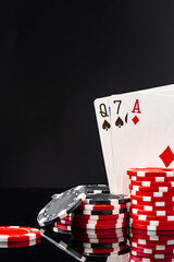 Playing cards and poker chips on black background