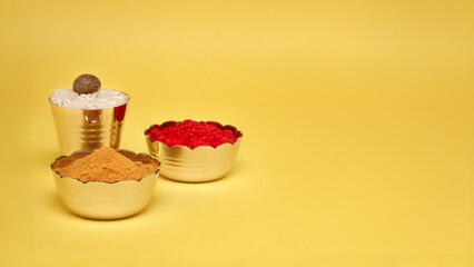 Small brass bowl with Sindoor or kumkum, Haldi, and a brass glass with rice and betel nut (supari)....