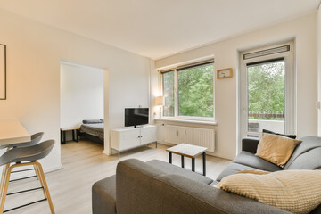 a living room with wood flooring and large windows looking out onto the trees in the photo is taken from inside