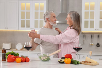Happy affectionate senior couple dancing in kitchen